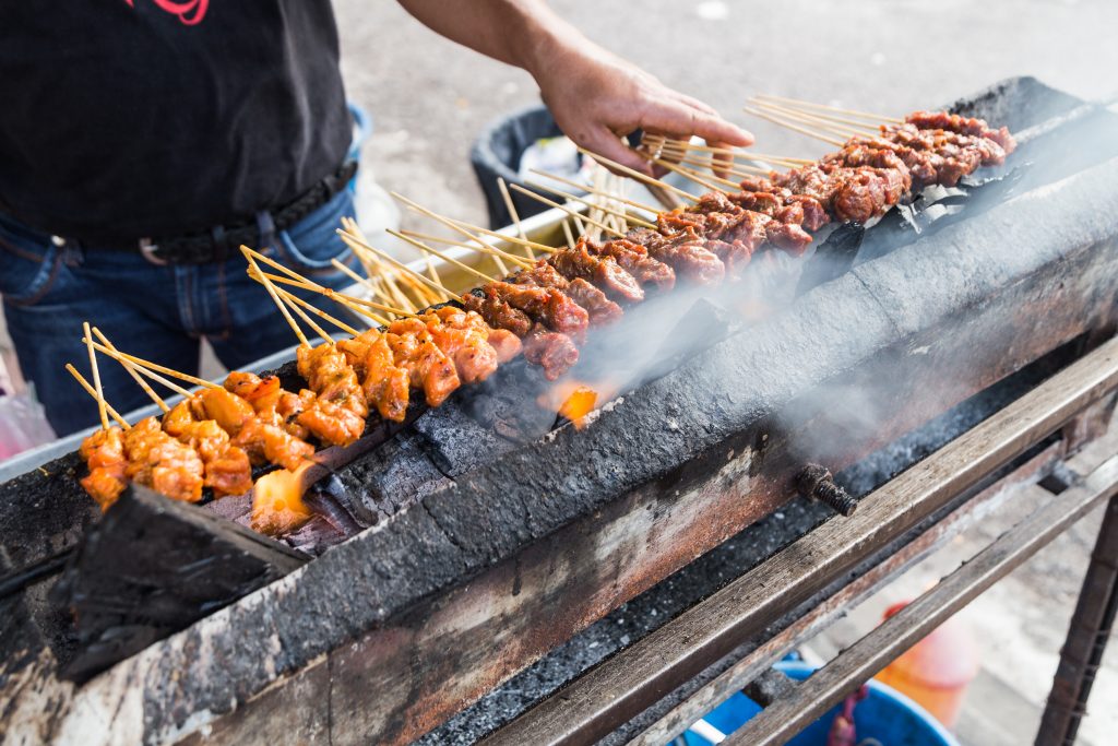 A common sight in hawker centres; vendors fanning the chargrilled bbq satay meat before serving them to customers. 